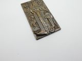 une plaque métallique ornée d'une croix, posée sur un fond blanc