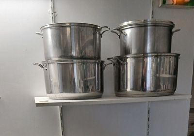 des casseroles et des poêles sont posées sur une étagère dans une cuisine