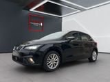 Une voiture noire est garée à l'intérieur d'un immeuble où une pancarte est accrochée au mur.