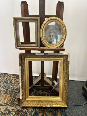 three frames on a stand with a mirror on top of it