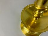 a close up of a gold candle holder on a white table