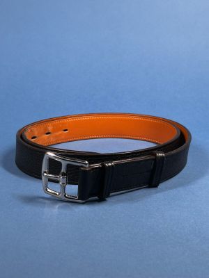 a close up of a black and orange belt on a blue surface
