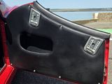une voiture rouge dont une portière est ouverte, garée sur le bord de la route