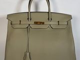 un sac à main en cuir beige avec des finitions dorées sur la poignée