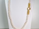 collier de perles avec un fermoir en or et des perles, sur un mannequin blanc