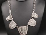 un collier en argent présenté sur un mannequin, sur fond noir