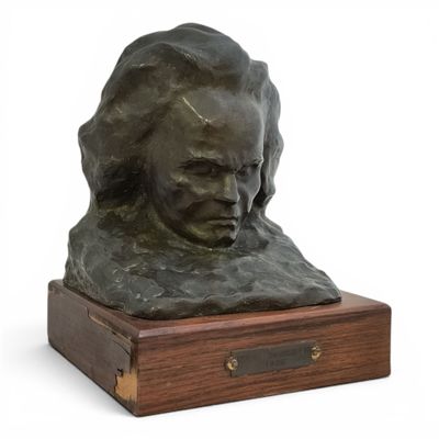 un buste en bronze représentant une femme, posé sur un socle en bois