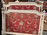 un lit orné d'un motif rouge et or dans une chambre