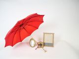 a red umbrella and a picture frame on a white surface