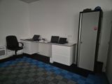 an image of a room with a refrigerator, desk, and computer