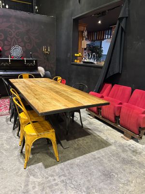tables and chairs in a room with a piano in the background