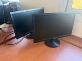 trois écrans d'ordinateur posés sur un bureau devant une fenêtre
