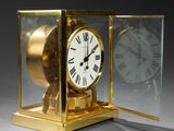 a gold clock with roman numerals in a glass case