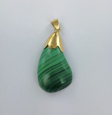 un gros plan d'un pendentif vert sur une surface blanche