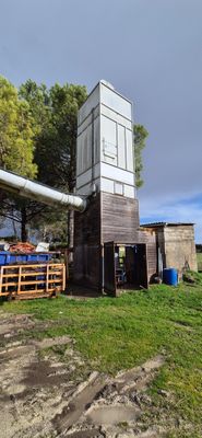 une petite construction en bois avec un toit, située dans un champ herbeux
