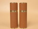 a pair of brown leather cylinder vases on a beige background