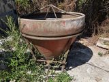 a rusted pot sitting on the ground next to a car