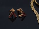 two pairs of gold and ruby earrings and a gold chain on a black surface