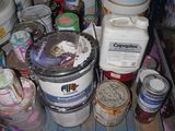 many cans of paint sitting on the floor next to a bucket of paint