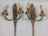 pair of antique brass wall sconces with candles on each of them