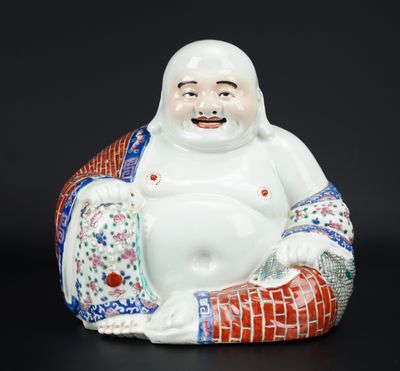 une figurine orientale représentant un Bouddha souriant assis sur un coussin