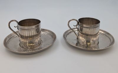 deux tasses et soucoupes en métal argenté, posées sur une soucoupe