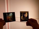 deux personnes tenant des photos d'un tableau dans une pièce