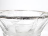 un saladier en verre transparent bordé d'argent posé sur une table