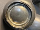 a silver teapot on the wall next to a knob