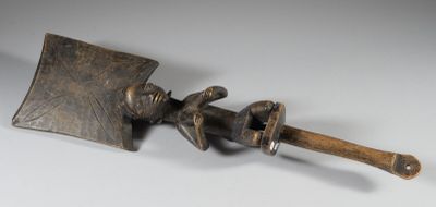 un objet métallique muni d'un manche en bois posé sur une surface blanche