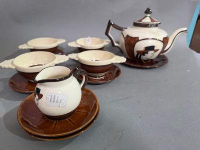 Plusieurs tasses et soucoupes sont posées sur une table, à côté d'une théière.