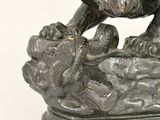 bronze statue of a lion on a rock with a bird perched on it ' s head