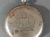 an old silver pocket watch sitting on top of a white table
