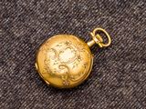 une image représentant une montre de poche en or posée sur un tapis