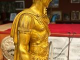 gold statue of a man holding a book in a room