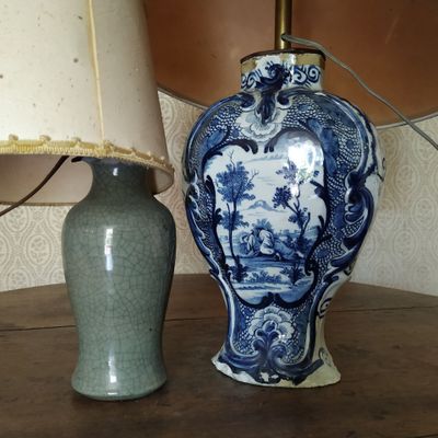 un vase bleu et blanc posé à côté d'une lampe sur une table