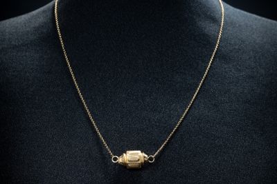a gold plated necklace with a gold plated pendant on a mannequin torso