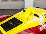 a yellow and red race car parked in front of a garage