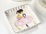 a plate with a picture of a woman in a pink dress on it