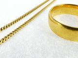 a gold ring and a gold chain on a white surface