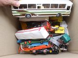 une personne tenant un bus miniature dans une boîte remplie de jouets
