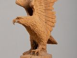 an old wooden statue of an eagle on a rock with its wings spread