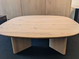 an oval conference table with a wooden base in a conference room