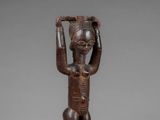a wooden statue of a man holding a basket on his head