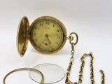 une montre de poche en or avec une chaîne et une loupe