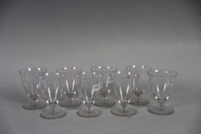 six empty wine glasses are lined up on a white surface