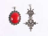 two silver and red stone pendants on a white background