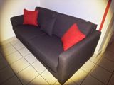 a black couch with red pillows in the corner of a room