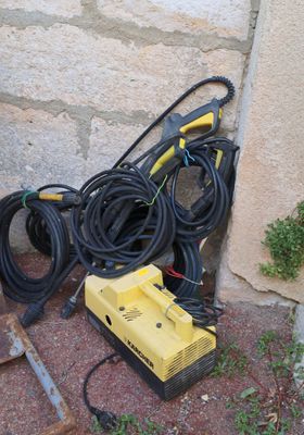 a yellow and black hoses and a yellow and black machine on the ground next to a brick wall