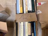 une boîte remplie de livres posée par terre à côté d'une pile de livres